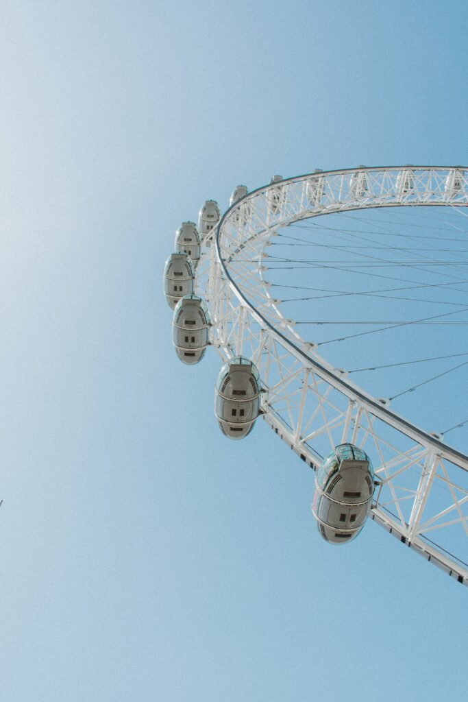 an upwards view of a large white ferris wheel against a blue summer sky