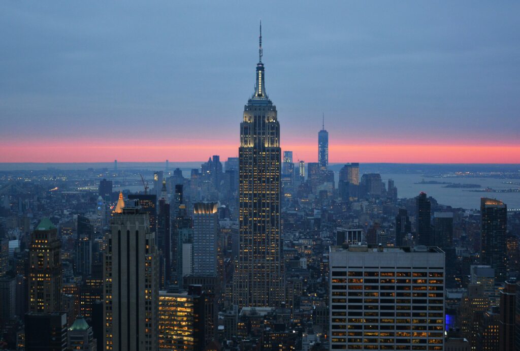 An image of the New York skyline with the empire state building as the main feature against a blue and pink sky