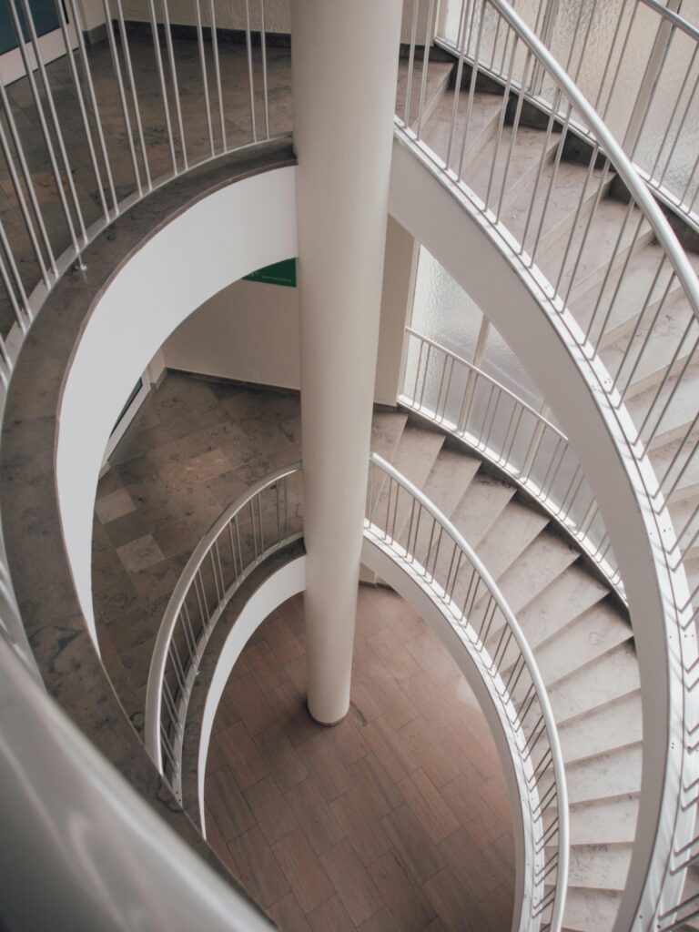 a white spiral staircase with a pole in the middle