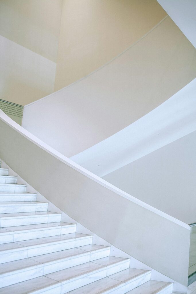A large, wide white staircase flight in spacious light hallway