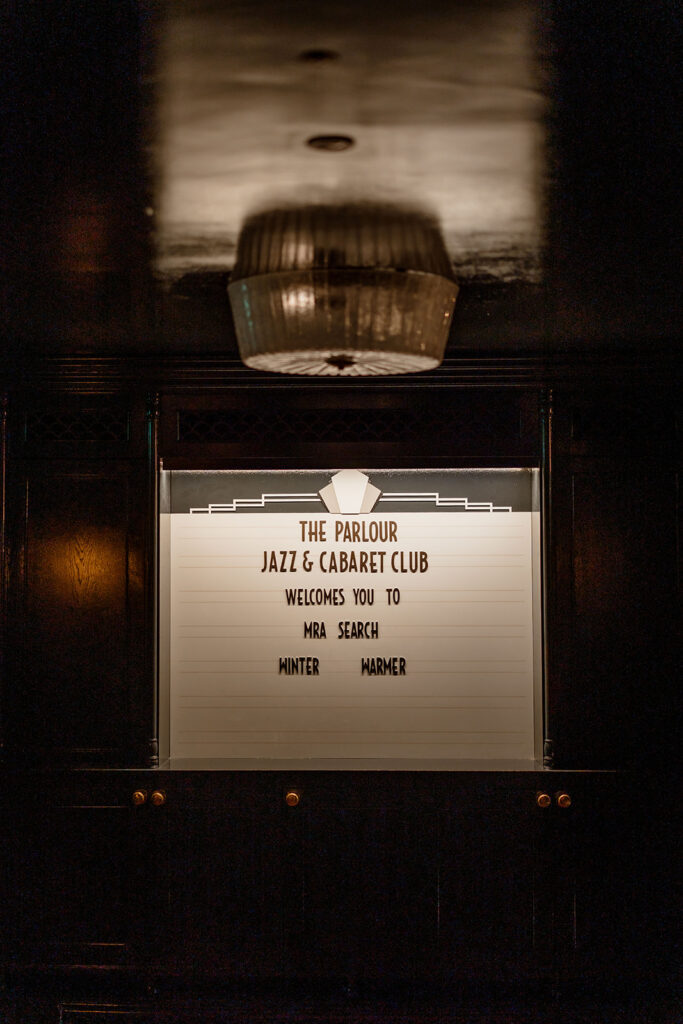 A photograph of a sign reading "The Parlour Jazz & Cabaret Club welcomes you to MRA Search Winter Warmer".