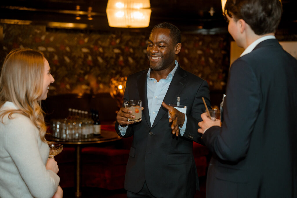 A photograph of three people talking.
