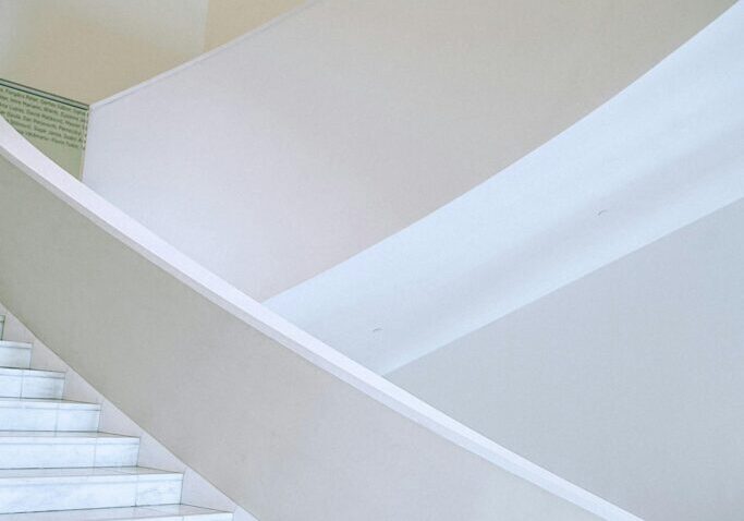 A large, wide white staircase flight in spacious light hallway